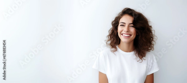Fototapeta portrait of a beautiful young happy woman laughing. a smiling woman wearing white sweater standing and smiling on gray background with copy space.