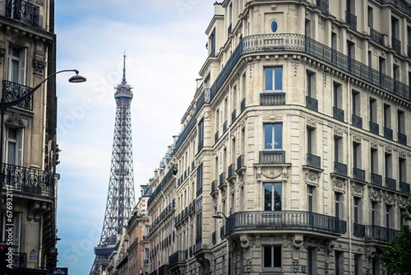Fototapeta View with a Haussmann-style building (flat) with the Eiffel Tower (Tour Eiffel) in the background in Paris, France on July, 16, 2023.