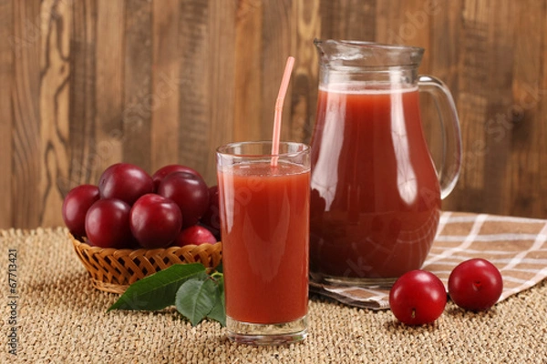 Fototapeta plum juice in a glass and pitcher, plums in a wicker basket on a