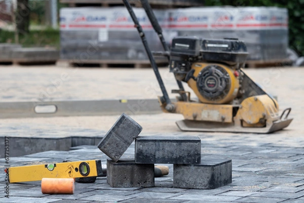 Fototapeta Construction site with paving slabs, a level and a construction machine