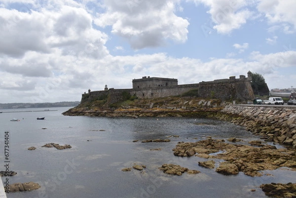 Fototapeta views of the castle of san anton in la coruña, spain. Blue sky with clouds and part of the sea and pier. nature.