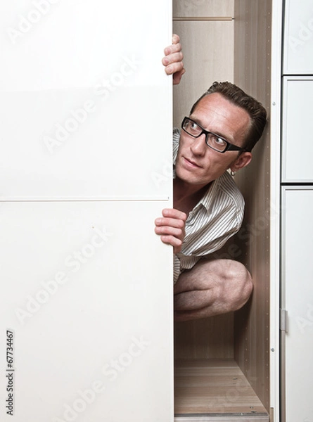 Obraz Prying man hiding inside white wardrobe  Copy space left