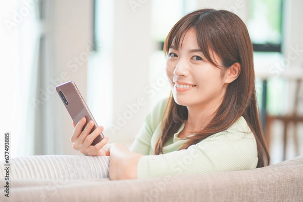 Fototapeta リビングでスマートフォンを操作する女性