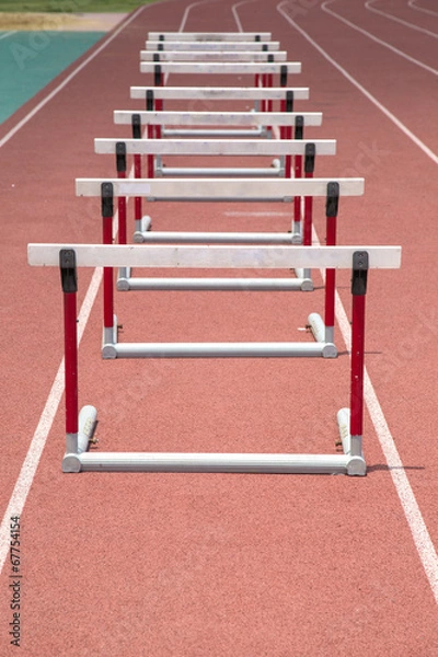Fototapeta Hurdles on the red running track