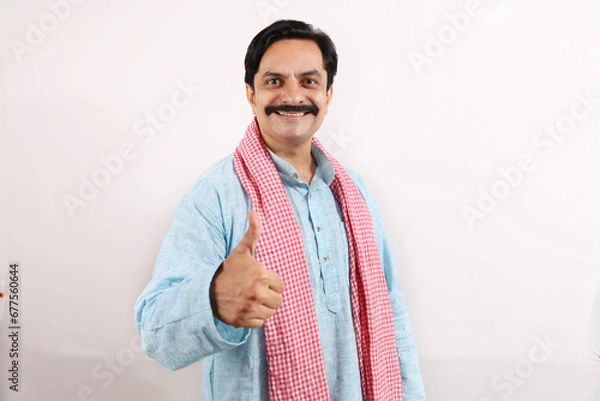 Obraz Happy rural Indian farmer standing in the white background, the passionate farmer full of enthusiasm shows sense of achievement and accomplishments, thumbs up.