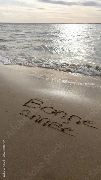 Fototapeta Message happy new year in french text sign means bonne annee written on beach sand background New Year coming concept