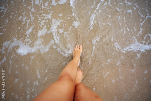 Fototapeta A beautiful girl in a bikini on a wild beach, bathing in the clear waves of the warm sea. a heavenly place and a beautiful model.