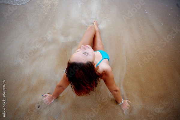 Fototapeta A beautiful girl in a bikini on a wild beach, bathing in the clear waves of the warm sea. a heavenly place and a beautiful model.