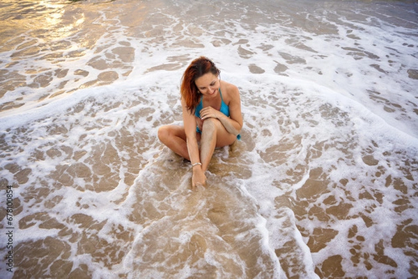 Fototapeta A beautiful girl in a bikini on a wild beach, bathing in the clear waves of the warm sea. a heavenly place and a beautiful model.