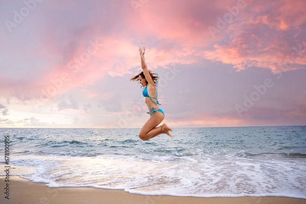 Fototapeta A beautiful girl in a bikini on a wild beach, bathing in the clear waves of the warm sea. a heavenly place and a beautiful model.