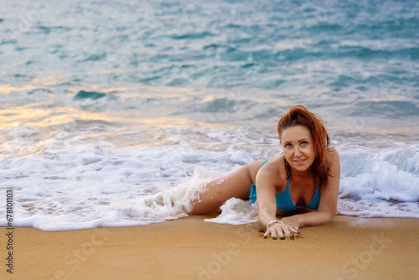 Fototapeta A beautiful girl in a bikini on a wild beach, bathing in the clear waves of the warm sea. a heavenly place and a beautiful model.
