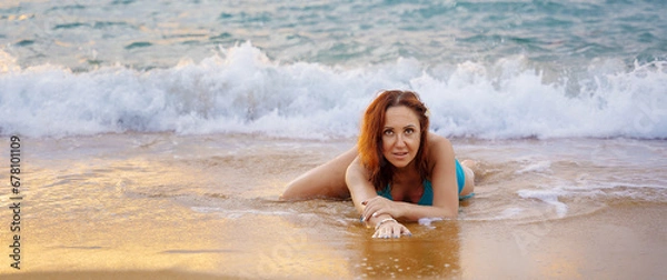 Fototapeta A beautiful girl in a bikini on a wild beach, bathing in the clear waves of the warm sea. a heavenly place and a beautiful model.