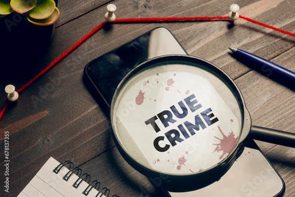 Fototapeta True crime concept: a magnifying glass above a smartphone on a detective's desk
