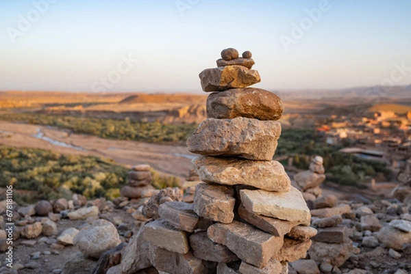 Fototapeta Stack of stone piled up on a hill in the Sahara Desert next to Ait Benhaddou during sunset