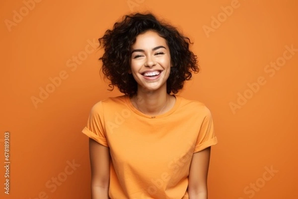 Fototapeta Portrait of a grinning woman in her 20s dressed in a casual t-shirt against a soft orange background. AI Generation