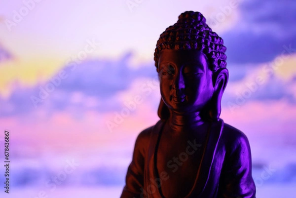Fototapeta Buddha Purnima and Vesak day concept, Buddha statue with low key light against beautiful and colorful background close up. Meditation
