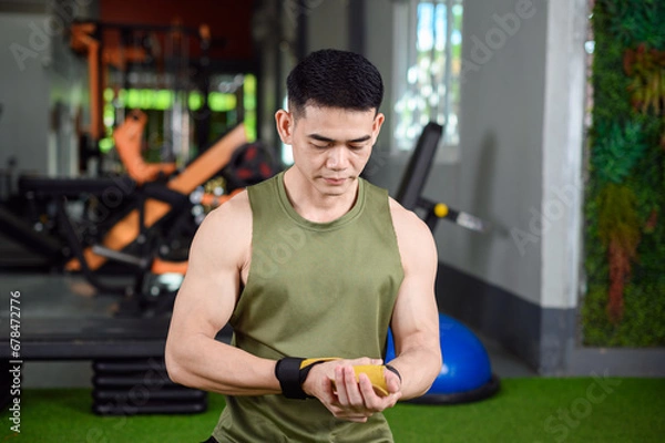 Obraz A man sits and adjusts his wrist brace.