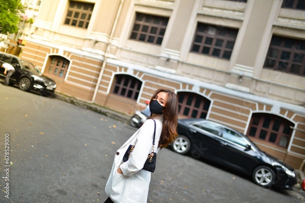Obraz Young woman wearing sunglasses in city, colorful buildings and feel the warm. Exploring this bustling metropolis is a true adventure