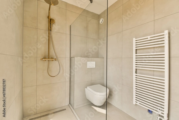 Fototapeta a bathroom with a toilet, shower and towel rack on the wall next to it is a glass enclosed shower door