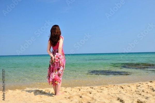 Obraz 海を眺めるピンクのドレスを着た女性の後ろ姿