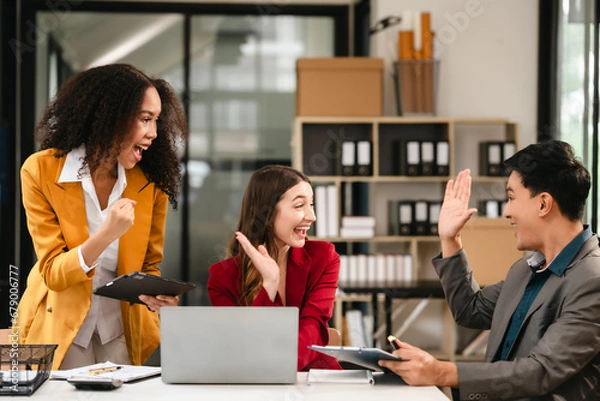 Fototapeta Diverse group of three professionals, two women and man, working together on design project around laptop. Product design team for industrial, working together, Asian man, African american people