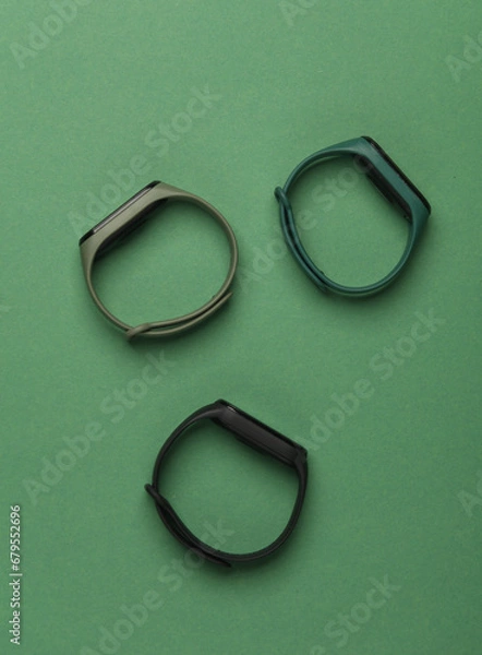 Fototapeta Three smart bracelets on a green background