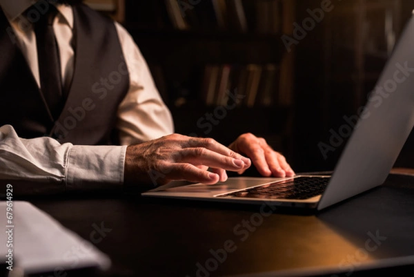 Fototapeta Concept of home office working. Close up businessman using laptop indoors. Business man wear formal waistcoat hands typing computer in dark room. Luxury expensive workplace