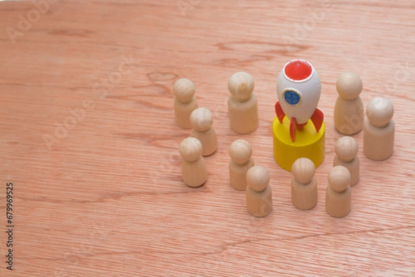 Fototapeta The wooden figures, clustered around a symbolic rocket, epitomized the success strategy of a cohesive team, reflecting the collective effort of teammates propelling the company towards global business