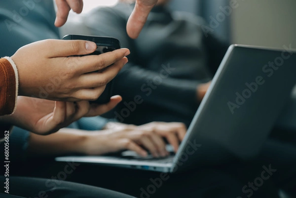 Fototapeta Three beautiful Asian girls using smartphone and laptop, chatting on sofa together at cafe with copy space, modern lifestyle with gadget technology or working woman on casual business concept