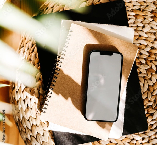 Fototapeta Blank path screen mobile phone with mockup on various notepads in sunlight with shadows