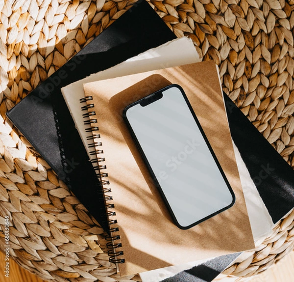 Fototapeta Blank path screen mobile phone with mockup on various notepads in sunlight with shadows