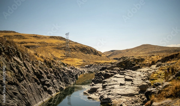 Fototapeta 
River near rock with yellow landscape, distant mountains and blue sky in the background in Espinar, Cusco, Peru.
