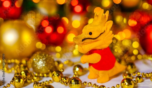 Fototapeta Small Chinese toy dragon on Christmas background. The concept of the holiday is Christmas, New Year. 2024. Space for text. Close-up. Christmas Card