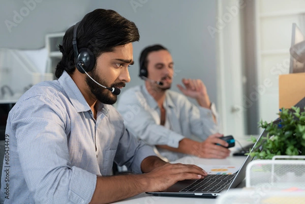 Fototapeta Indian customer service agent supporting customer by communicating information via headphone. Businessman on conference call with coworker and management, online quarterly result presenting. 