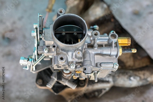 Fototapeta View of automobile carburetor. A carburetor (also spelled carburettor or carburetter) is a device used by a gasoline internal combustion engine to control and mix air and fuel entering the engine.