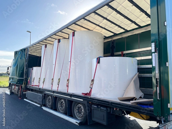 Fototapeta Loading, transporting and unloading large rolls of paper in a semi-trailer. Securing cargo with straps and locks for stability