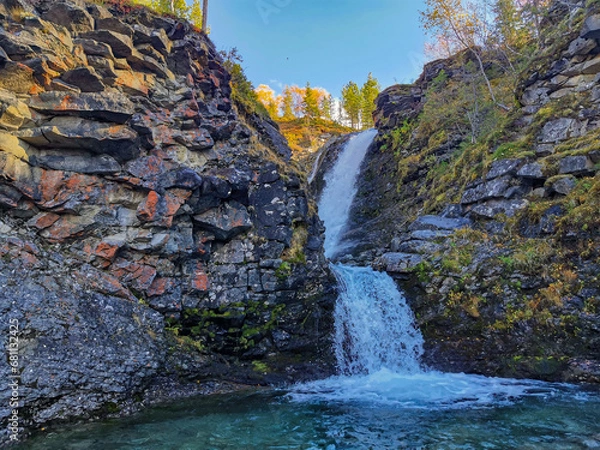 Fototapeta A beautiful waterfall in the autumn mountains beyond the Arctic Circle in the north, in Khibiny, Murmansk region. Panoramic view of a beautiful waterfall in the mountains in autumn, Kola Peninsula