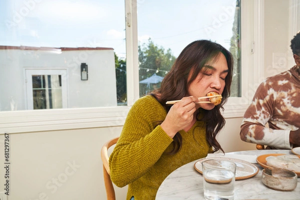 Obraz People eating dim sum at kitchen table taking bite