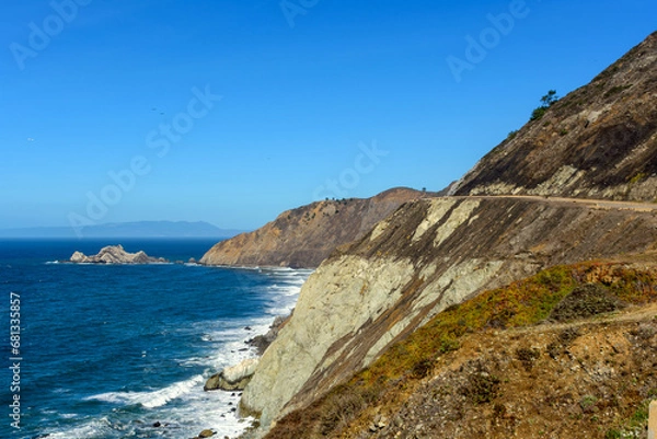 Fototapeta Scenic landscape of California coast showcasing the blue ocean, rugged cliffs, and a clear sky near Devils Slide trail