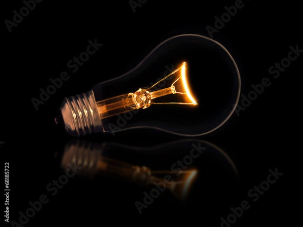 Fototapeta Lit light bulb on black background