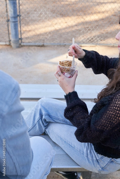 Obraz Couple eats yogurt and protein bar on bleachers outside