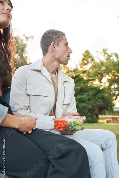 Obraz Couple snacks on vegetable platter in park