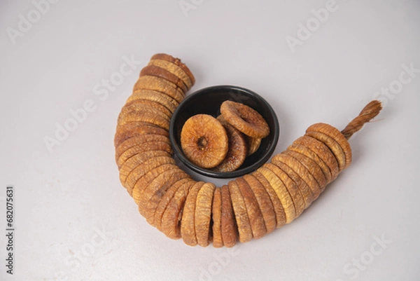Fototapeta Figs or dried figs on white bowl with white background, Figs or dried figs arranged in round shaped on the white background in a wooden bowl. The fig is the edible fruit of Ficus Carica