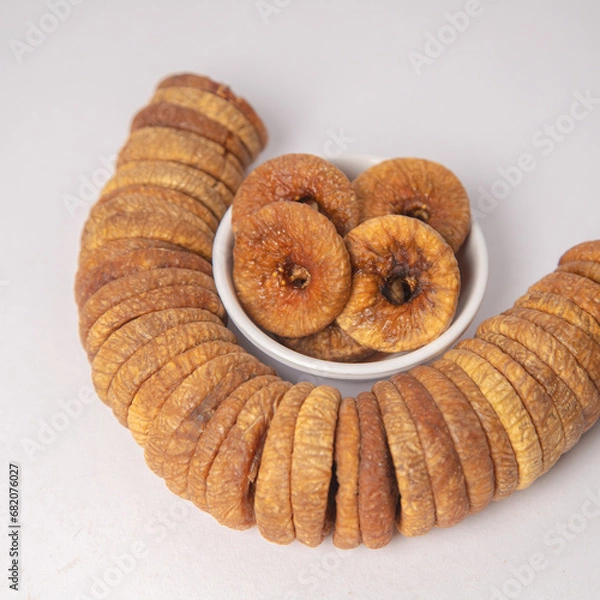 Fototapeta Figs or dried figs on white bowl with white background, Figs or dried figs arranged in round shaped on the white background in a wooden bowl. The fig is the edible fruit of Ficus Carica