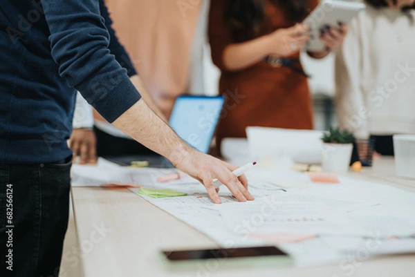 Fototapeta Multiracial corporate team in a creative office, collaborating on project coordination, financial planning, and sales strategies for company growth and profitability.