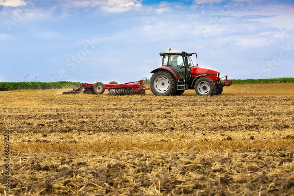 Fototapeta Tractor cultivating wheat stubble field, crop residue.