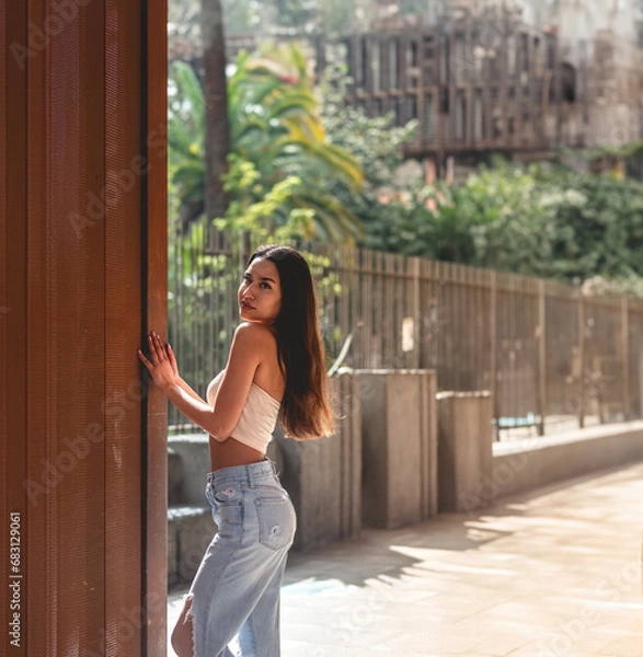 Obraz Urban vibes: stylish latino girl in jeans and little top posing against copper wall under sunlight, with big copy space