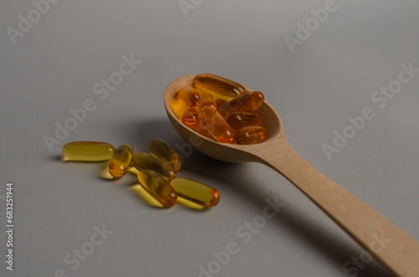 Obraz Omega 3 capsules in the wooden spoon.Cod liver oil capsules on the table. Healthy life style concept