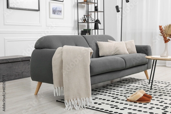 Fototapeta Stylish living room interior with comfortable sofa, blanket, slippers and side table