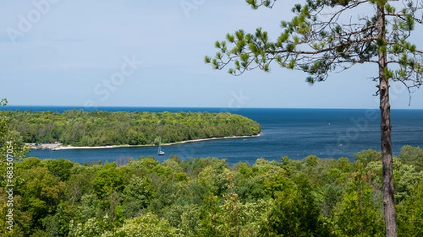 Obraz Scenic overlook view of the Green Bay of Lake Michigan in Door County, Wisconsin, with green vegetation, a cove with boats, and the blue water and sky.